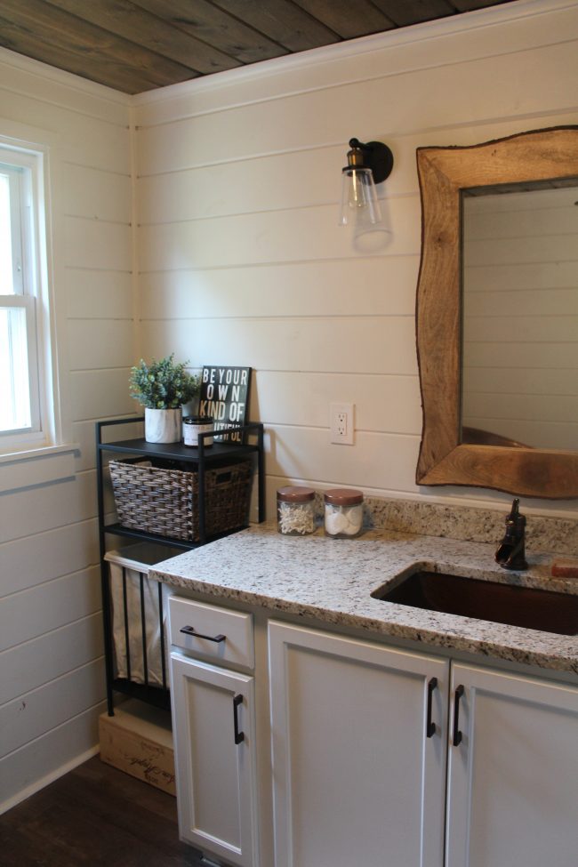 A modern farmhouse bathroom makeover - with a copper tub, copper sink, wood plank ceiling, white shiplap walls, LVT flooring, and granite counter tops.