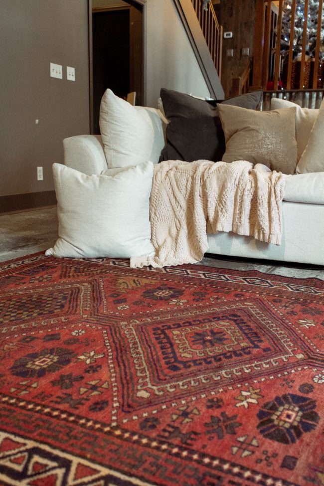 A vintage area rug in our living room || Slowly but surely decorating our new home! || Kansas City life, home, and style blogger Megan Wilson shares a peek at a new rug in her home's living room // concrete floors, vintage area rug, Christmas tree, fireplace 