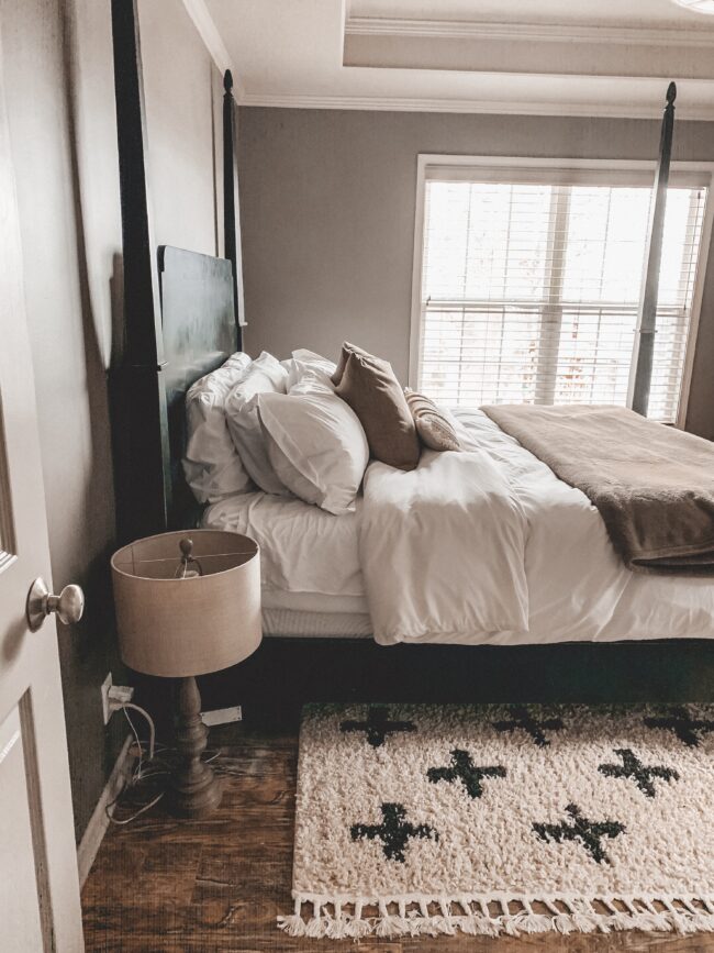 Black and white area rug in master bedroom, white bedding, black four poster bed || Neutral master bedroom design, plus the plans we have to change things up! Kansas City life, home, and style blogger Megan Wilson shares her master bedroom design plans and inspiration