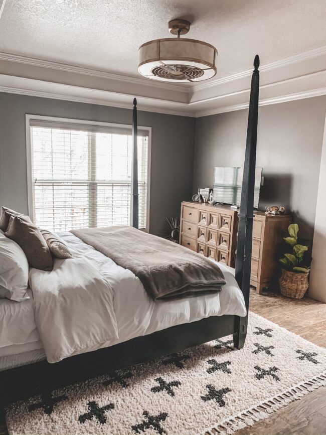 Black and white area rug in master bedroom, white bedding, black four poster bed || Neutral master bedroom design, plus the plans we have to change things up! Kansas City life, home, and style blogger Megan Wilson shares her master bedroom design plans and inspiration