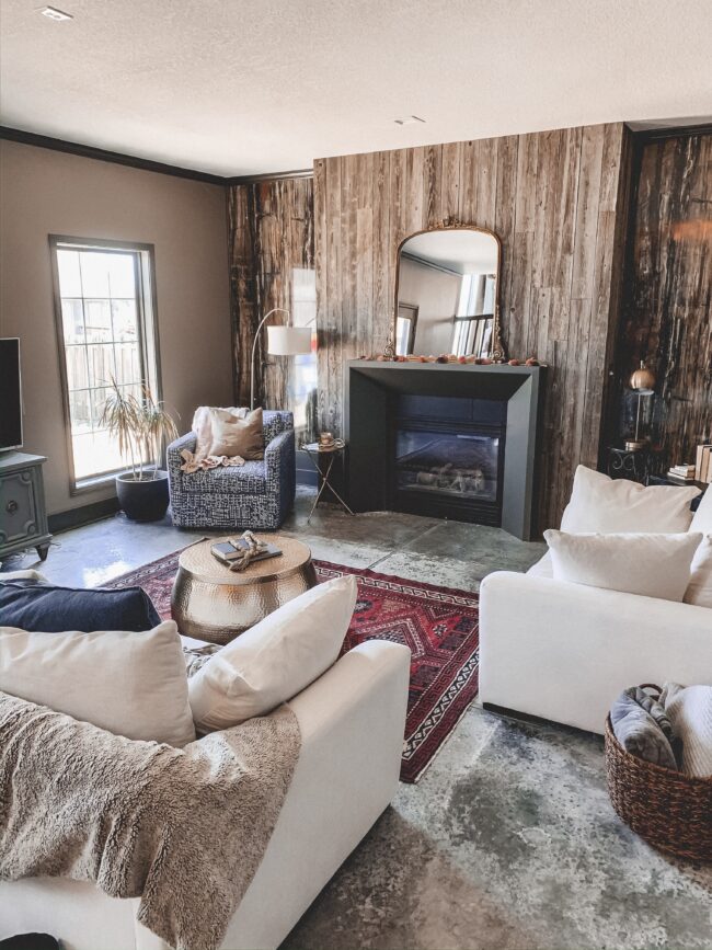 Gold Mirror over the Fireplace in the Living Room, vintage rug, black modern fireplace, white couch, wood planked fireplace wall || Kansas City life, home, and style blogger Megan Wilson shares a living room update