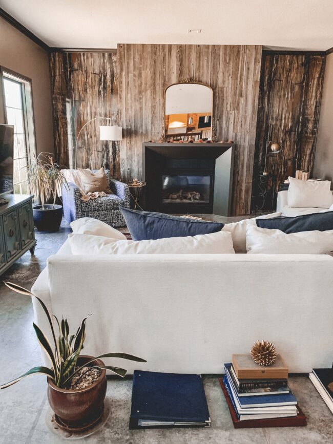 Gold Mirror over the Fireplace in the Living Room, black modern fireplace, navy throw pillows, white couch, wood planked fireplace wall || Kansas City life, home, and style blogger Megan Wilson shares a living room update