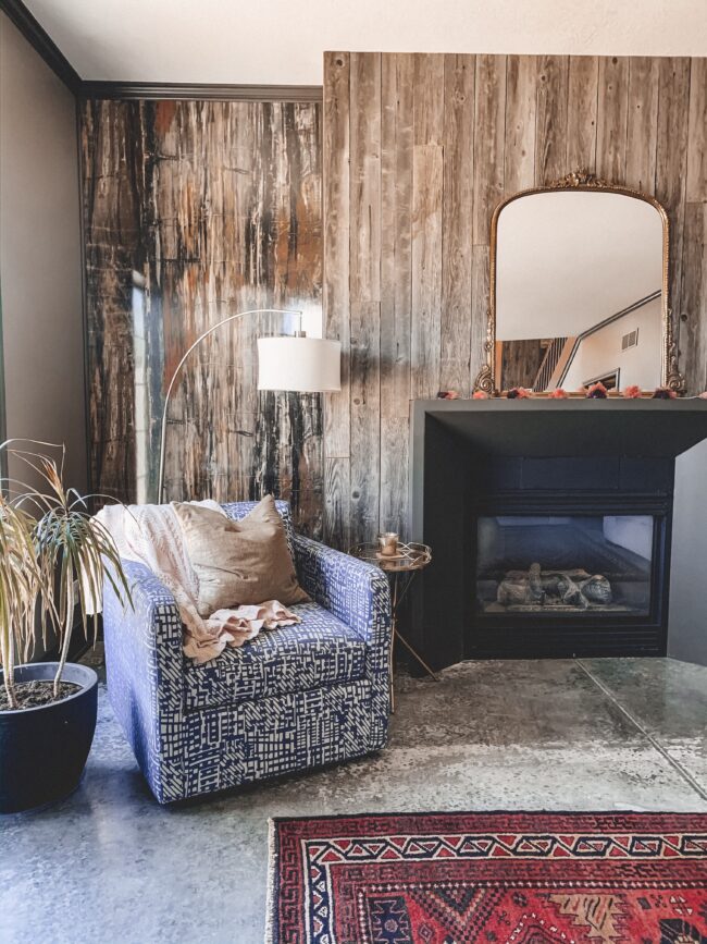 Gold Mirror over the Fireplace in the Living Room, vintage rug, blue chair, black fireplace, wood planked fireplace wall || Kansas City life, home, and style blogger Megan Wilson shares a living room update