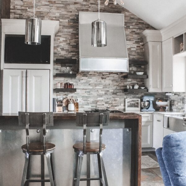 Home Tour: our rustic meets modern kitchen! Kansas City life, home, and style blogger Megan Wilson shares a tour of her new home's kitchen with pendant lights over the island, stainless range hood, stone backsplash, granite and wood countertops, metal and wood accents, stainless farmhouse kitchen sink, and open shelves.