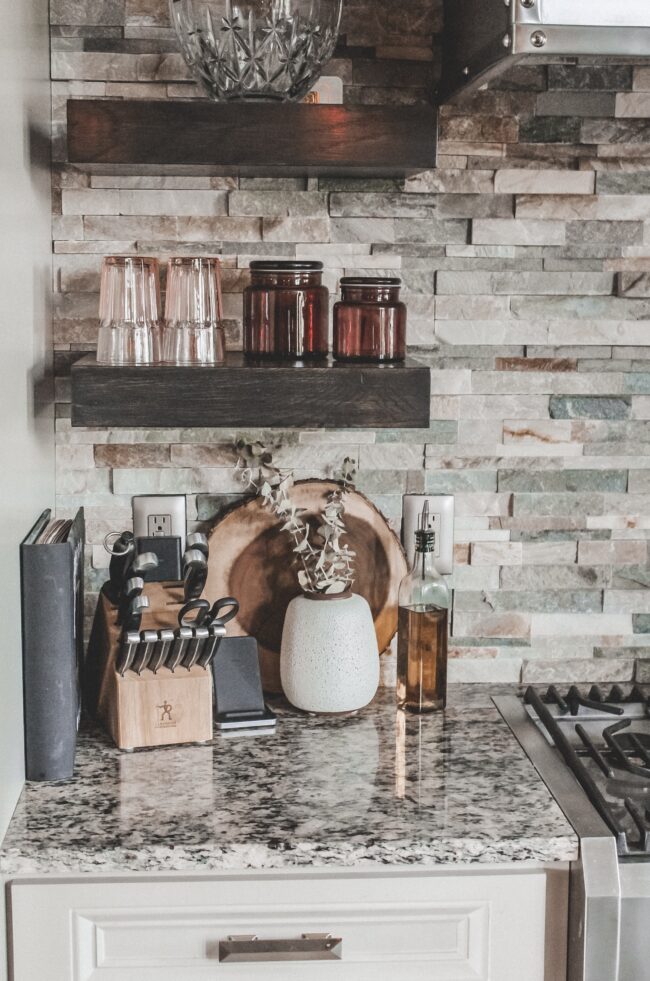 Home Tour: our rustic meets modern kitchen! Kansas City life, home, and style blogger Megan Wilson shares a tour of her new home's kitchen with stone backsplash, granite and wood countertops, metal and wood accents, stainless farmhouse kitchen sink, and open shelves. 