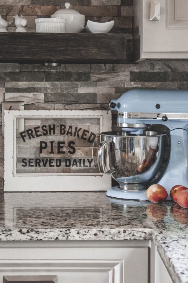 Home Tour: our rustic meets modern kitchen! Kansas City life, home, and style blogger Megan Wilson shares a tour of her new home's kitchen with stone backsplash, granite and wood countertops, metal and wood accents, stainless farmhouse kitchen sink, and open shelves. 