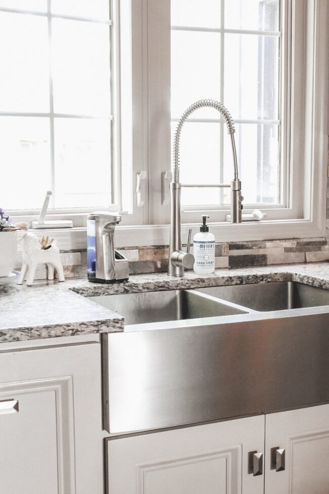 Home Tour: our rustic meets modern kitchen! Kansas City life, home, and style blogger Megan Wilson shares a tour of her new home's kitchen with stone backsplash, granite and wood countertops, metal and wood accents, stainless farmhouse kitchen sink, and open shelves. 