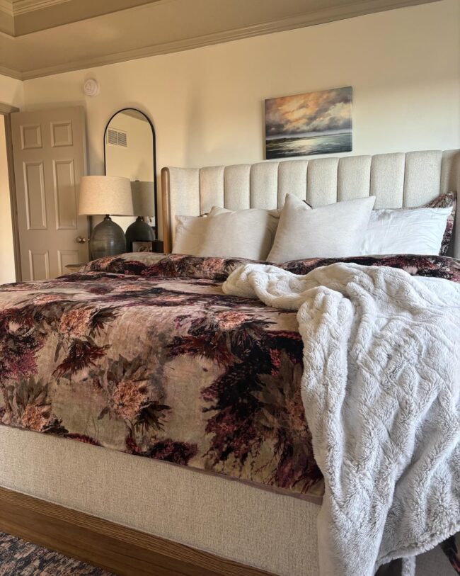 Feminine Primary bedroom with upholstered king size bed, floral duvet, and organic modern touches